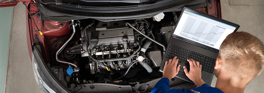 Mechanic with laptop under a car's bonnet
